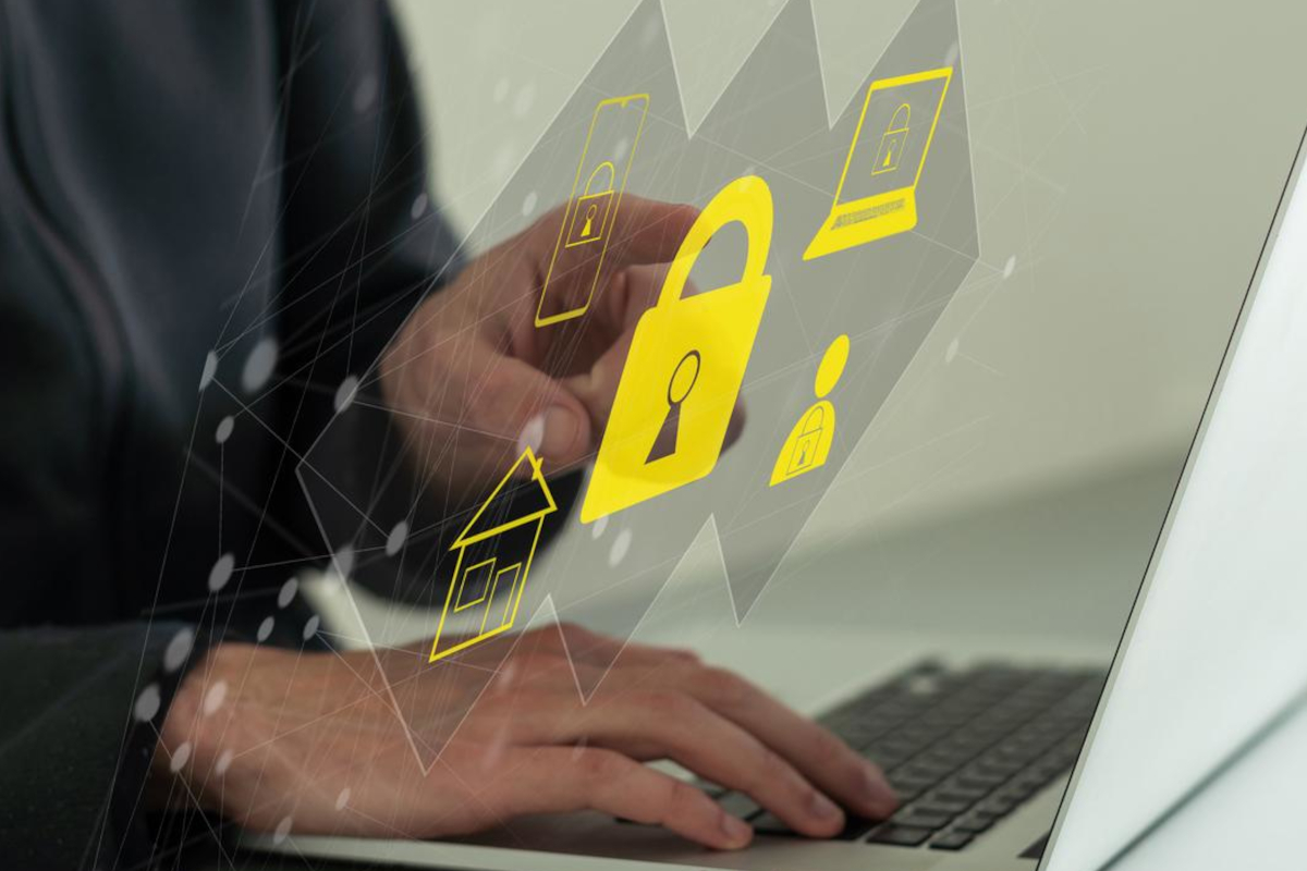 Man typing on keyboard while security icons are floating around him.