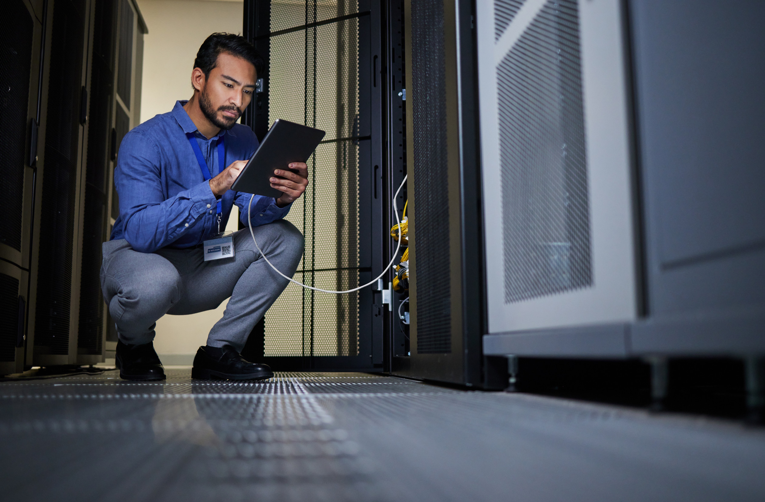 Engineer in server room using a tablet to connect to computer