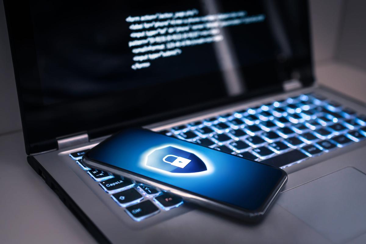 Laptop and smartphone displaying a security shield icon.
