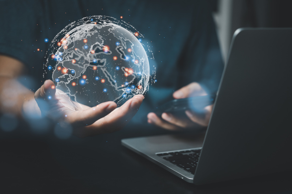 A man holding a digital globe in his palm and the globe has blue and red dots